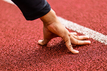 Athlete's Hand on Starting Line, Ready to Sprint on Red Track