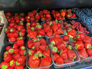 Fresh strawberries and blueberries arranged in containers at a local market