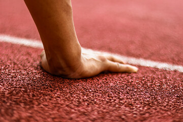Athlete's hand on track starting line, ready to sprint, close-up detail