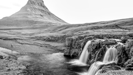 Summer evening at Kirkjufell waterfalls in Iceland featuring dramatic sunset and lush scenery