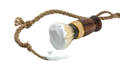 Close-up of a shaving brush with lather and rope loop against a black backdrop