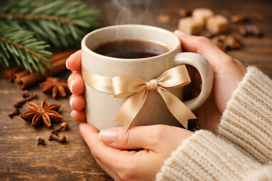 Festive Warmth: Hands Holding a Mug of Steaming Beverage with Spices - Powered by Adobe