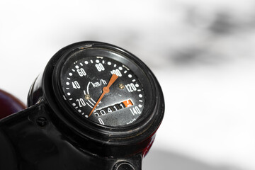 Closeup photo of a round black speedometer of an old Soviet motorcycle