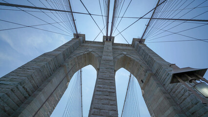 Obraz premium Brooklyn Bridge stone pillars captured from below highlighting structural details and grandeur