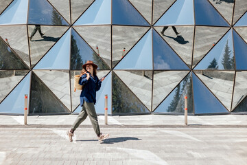 Woman walks near geometric glass wall in city