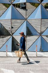 Walking by a reflective wall with a bag