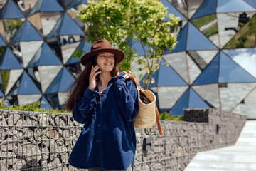 Woman walking near modern building with phone