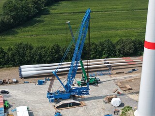 Luftbild einer Baustelle f&uuml;r eine neue Windkraftanlage. Gittermast-Raupenkran und Rotorbl&auml;tter, Windradfl&uuml;gel, Luftbild, Vorbereitung, Baustelle, Energiewende