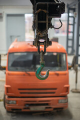 Fototapeta premium In focus is the green hook of a replacement crane with an orange cabin. High quality photo