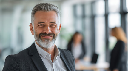 Portrait of a successful senior business consultant smiling confidently in a modern office with natural light wearing professional attire