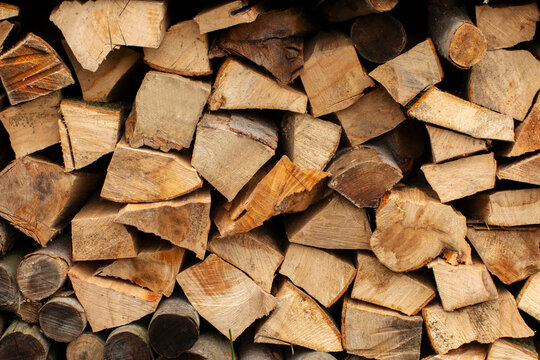 Firewood stacked neatly in pile, logs cut into different sizes and shapes, closeup shot - Powered by Adobe