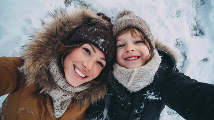 Top view of mother and child enjoying playful winter break on snowy ground in rural winter landscape with warm clothing and natural smiles