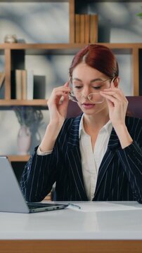 Businesswoman suffers from headache, tired from overwork, information overload. Stressed employee business woman suffering fatigue rubbing dry eyes at workplace in office.