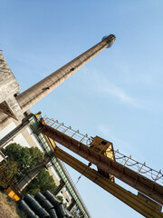 Low angle view of industrial chimney and yellow crane