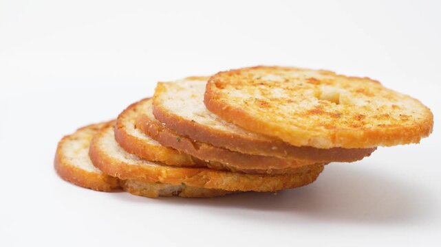 Several baked bread slices arranged in a fan shape rotate gently on a white surface. The video showcases layered composition, crunchiness, and baked color through smooth rotation.