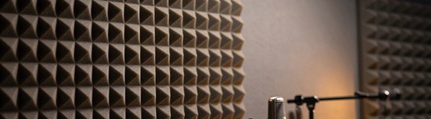 textured acoustic foam panel dimly lit grey studio wall soft focus warm golden light