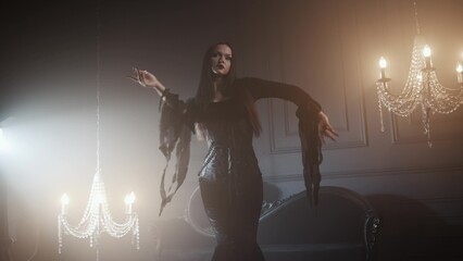 Gothic fashion portrait showing a femme fatale in black godet dress with corset, featuring long straight hair, dark makeup, and set in an opulent dark interior.