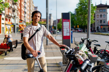 Indian man on an urban sidewalk, holding a shared electric bicycle, promoting eco friendly city transportation