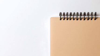 Minimalist stationary: a spiral notebook with neutral tan pages lies adjacent to a blank white space, offering room for creative content or text placement for design projects.