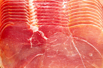 Slices of Appetizing Jamon Serrano on a wooden board, top view. Close-up.