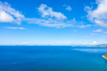 Obraz premium Expansive view of the deep blue Ionian Sea with a distant coastline and scattered clouds under a bright sky. The scene highlights the clarity and vivid color of the Mediterranean seascape.