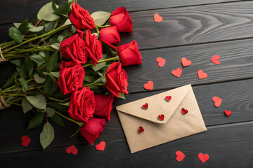 Red roses bouquet and heartfelt love letter envelope on a dark wooden background