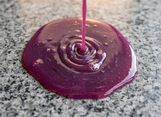 a pink liquid splashing onto a gray, speckled granite surface, creating a mesmerizing, marbled pattern