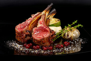 Rack of Lamb - The meat is cooked to medium rare, giving it a pink hue and a tender texture. The dish is garnished with roasted garlic, red currants, and a sprig of rosemary