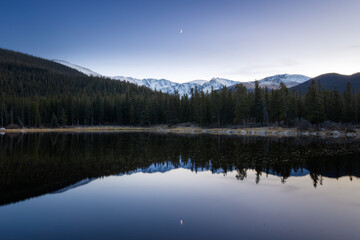 Snow mountain reflection with a crescent moon at dusk on Echo lake Idaho Springs, Colorado 