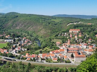 Panoramic viewpoint over Bardo Śląskie and the Kłodzko Valley. Green hills, the Nysa Kłodzka River and a small town create a peaceful landscape of southern Poland.