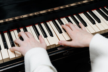 female pianist hands on black and white piano keyboard, close-up view, young woman playing piano, professional musician