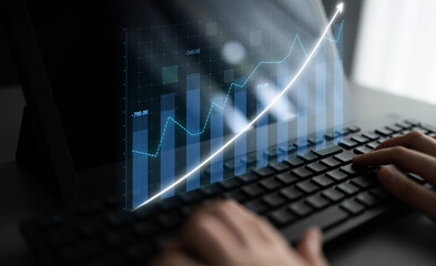 A focused shot of hands on a keyboard while analyzing financial data on a digital screen. The graph shows upward trends indicating business growth and success. Impute