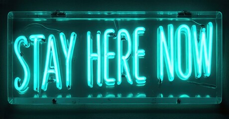 Bright turquoise neon sign displays words stay here now. Dark background emphasizes glowing text. Simple rectangular frame surrounds message.
