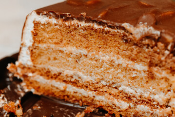 large brown sliced chocolate cake with cream and peanuts, sweet tasty food for holydays and celebrating, partly eaten, selective focus