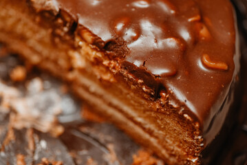 large brown sliced chocolate cake with cream and peanuts, sweet tasty food for holydays and celebrating, partly eaten, selective focus