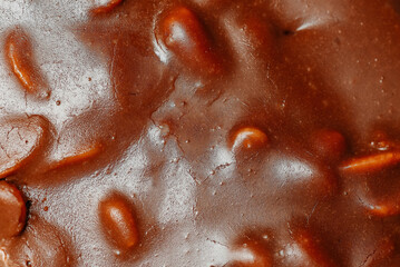 large brown sliced chocolate cake with cream and peanuts, sweet tasty food for holydays and celebrating, background
