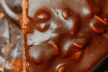 large brown sliced chocolate cake with cream and peanuts, sweet tasty food for holydays and celebrating, partly eaten, selective focus