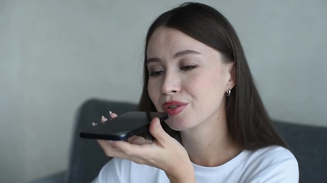 young beautiful caucasian brunette woman recording voice message, smiling widely, casual clothes, white T-shirt, talking by smartphone