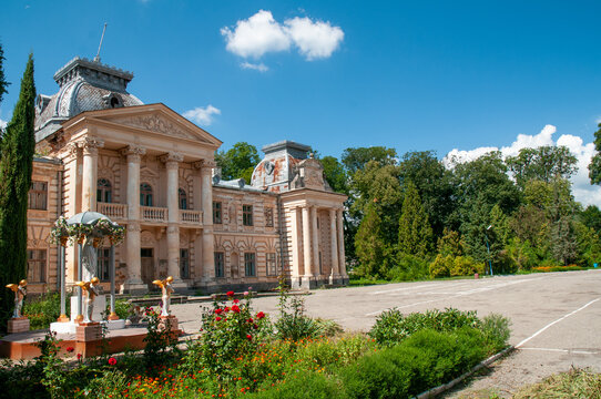Koropets Palace in Ternopil region, dilapidated neoclassical baroque manor with crumbling columns, dome and overgrown gardens under a clear summer sky, neglected grandeur preserved