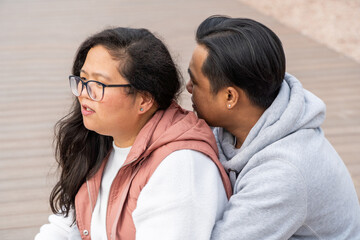 Multiethnic asian couple on a romantic moment talking while sitting on a park