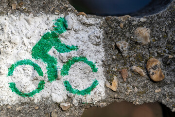 Bicycle symbol painted on surface near trail in natural setting during daylight
