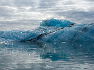 Blue iceberg glistening in sunlight floating in Iceland's Jokulsarlon Glacier Lagoon