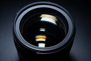 Detailed front view of camera lens glass with strong reflections in studio lighting.