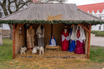 Nativity scene displayed in outdoor setting during festive season in a village square