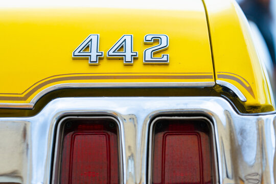Oldsmobile 442 rear emblem on bright yellow muscle car with chrome trim.