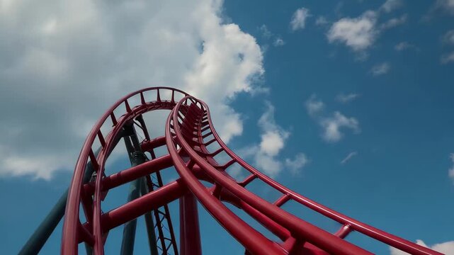 Roller coaster ride at amusement park with bright blue sky and clouds in the background