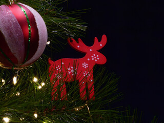 Red wooden reindeer ornament on Christmas tree branch