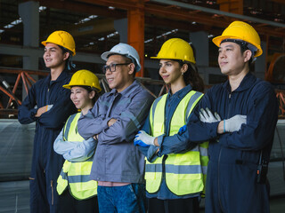 group five industrial worker standing together in factory setting, wearing safety helmets and reflective vest. image represent teamwork, safety compliance, professionalism in industrial environment.