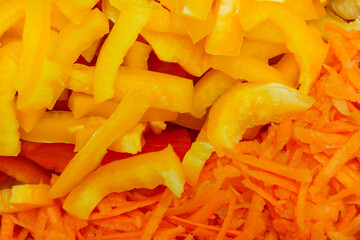 Freshly chopped yellow bell pepper and grated carrot on a cutting board for meal prep