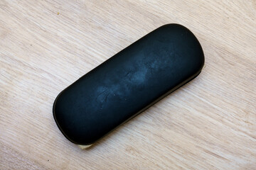 Black case placed on wooden surface without any objects around it during daylight